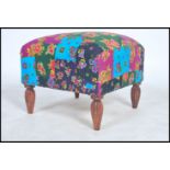 A vintage 20th century large cube footstool raised on four carved legs with a floral patchwork