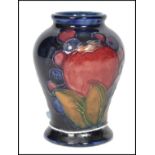 A 20th century William Moorcroft tubelined baluster vase decorated in the iconic pomegranate and