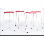 A set of four dot stool style stools, white coated tubular frames with a curricular red plastic