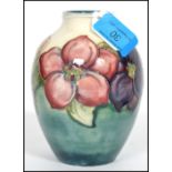 A c1950s Walter Moorcroft globular vase having tube lined and painted floral decoration on a blue