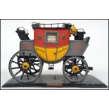 A vintage style model of a London English Mail Coach, in yellow colourway on a plinth base with