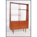 A 1970's Danish teak wood room divider bookcase being raised on tapered legs with cupboard base with