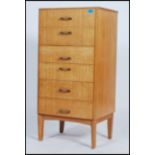 A retro 1970's upright natural oak pedestal chest of drawers being raised on tapering legs with an