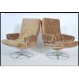 A pair of retro 20th century button back upholstered wing back style swivel armchairs raised on