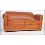 An early 20th century tan leather club sofa / settee having shaped sides and raised on square stub