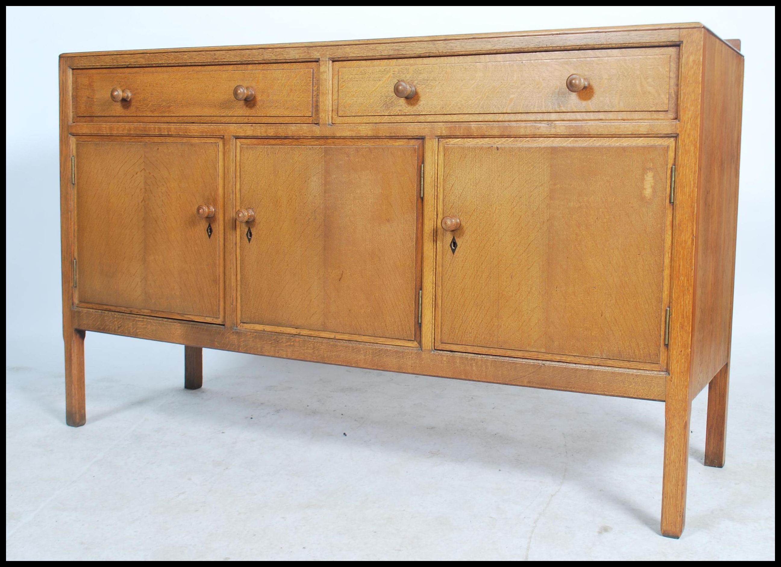 A Heal`s mid century oak sideboard, two long drawers (with Heal & Sons roundel to top drawer)