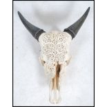 An Indian / Persian caved cow skull and horns, having stunning fret pierced decoration to the