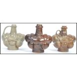 A group of three studio pottery vases of unusual form having shaped bodies with tapering necks, in