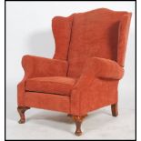 A 20th century good quality Chesterfield revival wing back armchair having scroll ends raised on