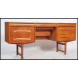 A 1970's retro Danish inspired teak wood writing table desk raised on shaped legs with a bank of