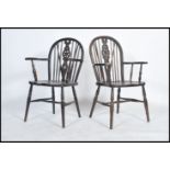A pair of mid century beech and elm wood wheelback dining chairs being raised on turned legs
