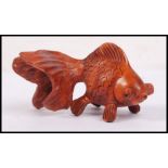 An oriental carved wooden netsuke in the form of a carp fish with large bulging eyes.