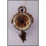 An unusual brass cased roman fish eye ball clock with bell to bottom and swing handle, the dial