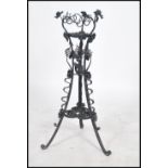 A stunning 20th century ebonised wrought iron scroll work planter / plant stand raised on tri-pod