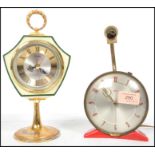 A vintage retro 20th century Metamec clock raised on a red plastic stand along with another clock by