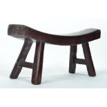 A 19th century Chinese hard wood lacquered neck rest / pillow with curved seat raised on shaped