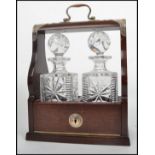 A mahogany and silver white metal mounted twin bottle Tantalus having fold out front with swing