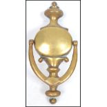 An early 20th century large brass door knocker of oval form with shaped finial top and swag drop,