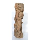 A hand carved wooden column of large form having a highly detailed putti holding the top of the