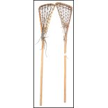 A pair of vintage 20th century Lacrosse sticks of wooden construction with nest tops. Measures: