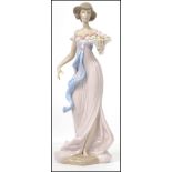 A Lladro ceramic figure of a young lady holding a basket of flowers - the base with impressed No.