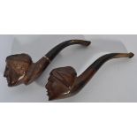 Two early 20th century briar wood pipes having ebonised horn mouthpieces with detailed carved