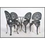 A vintage retro 20th century cast aluminium garden table and four chairs having a pierced