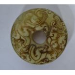 An Oriental jade carved bi of roundel form with hole to centre depicting dragons to both sides.