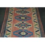 A 20th century carpet / rug runner salmon ground decorated throughout with geometric patterns.