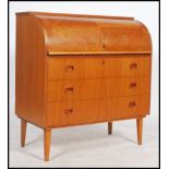 A retro 20th century Danish inspired teak wood roll top desk having an appointed interior and raised