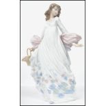 A Lladro ceramic figurine entitled ' Spring Splender ' of a lady holding a floral basket in