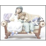 A Lladro ceramic figurine group entitled ' Big Sister ' depicting two children on a sofa with dog,