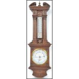 An early 20th century Negretti and Zambra oak aneroid barometer having carved classical columns with