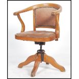 A vintage early 20th century Captains swivel armchair raised on a quadruped base with swivel