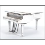 A sterling silver miniature grand piano raised on