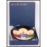 A Moorcroft ceramic tube lined pin dish coaster decorated in the Xmas Candlelight pattern with