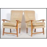A pair of retro 20th century open framed beech wood fireside armchairs each being upholstered with a