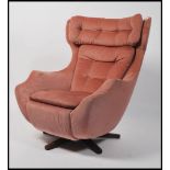 A 1960's Parker Knoll large batwing swivel egg chair - armchair being raised on a teak quadruped