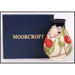 A Moorcroft ceramic tube lined vase decorated in the Rosehip pattern with impressed marks and