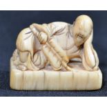 A believed 8th century Japanese ivory netsuke in the form of courtesan in repose holding a fan and