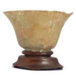 19th century Chinese jade libation cup raised over a wooden socle plinth base. The cup of lozenge