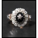 An unusual rose gold diamond and onyx cluster ring  with central oval cut onyx having a diamond