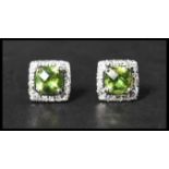 A pair of 925 silver earrings set with a square cut peridot stone surrounded by a halo of CZ