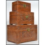 A graduated set of three 20th century Camphor wood boxes, carved panels, hinged lids and brass