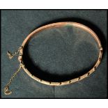 A hallmarked 9ct gold bangle bracelet having a half engraved design with ball finials to top and