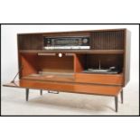 A 1950's retro Grundig laquered walnut radiogram being raised on tapering legs with decorative