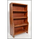 An early 20th century walnut Arts and Crafts inspired waterfall open dwarf bookcase, having four