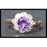 A hallmarked 18ct gold amethyst and diamond cluster ring set with a central round cut amethyst
