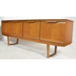A 1970's retro teak wood sideboard of low and wide form being raised on tapering legs. Above, the