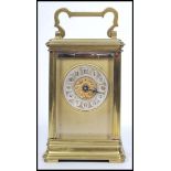 An early 20th century brass carriage clock hacing gilded face with enamel button numerals with